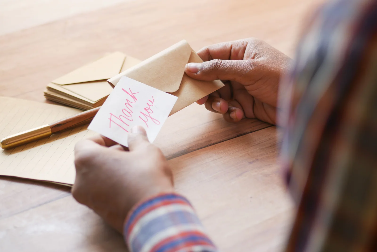 Person holding a handwritten thank-you card and envelope.