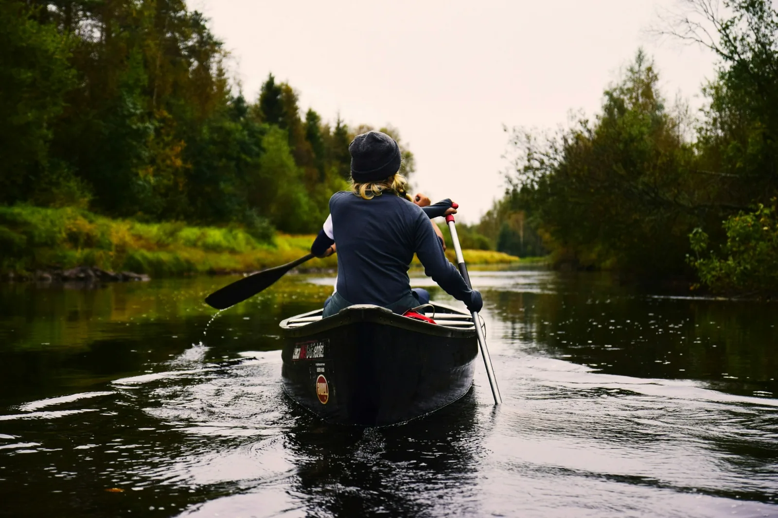 A person paddling a canoe on open water