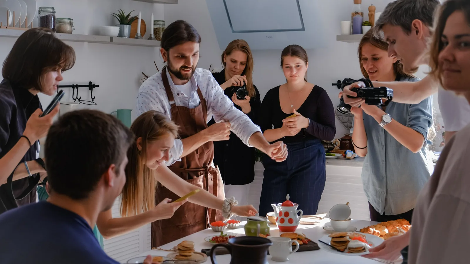People photographing dishes on a kitchen table