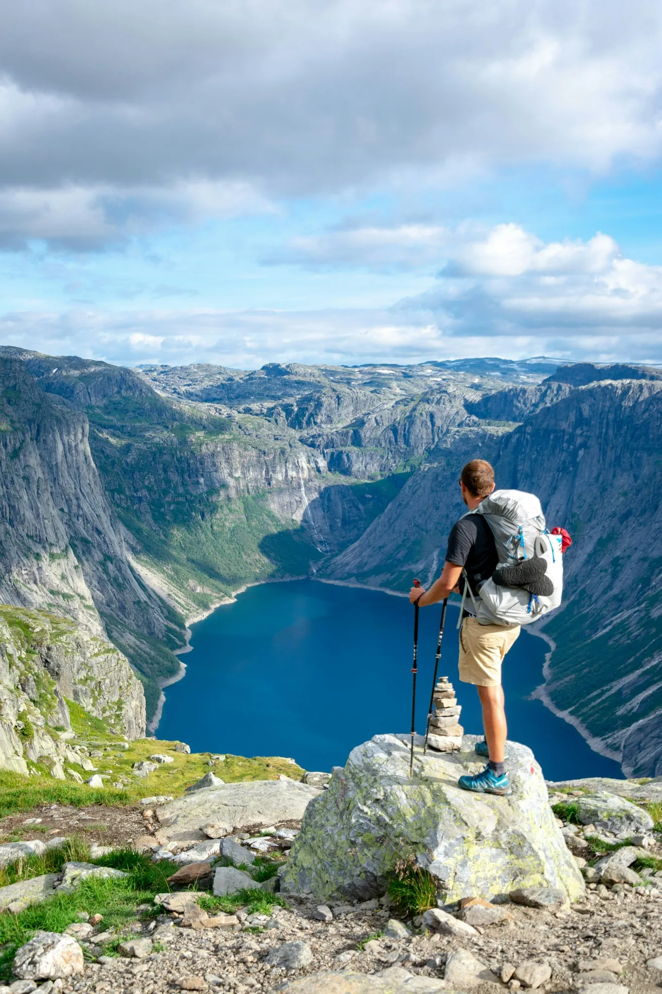 A hiker with a backpack standing on a rocky mountain summit