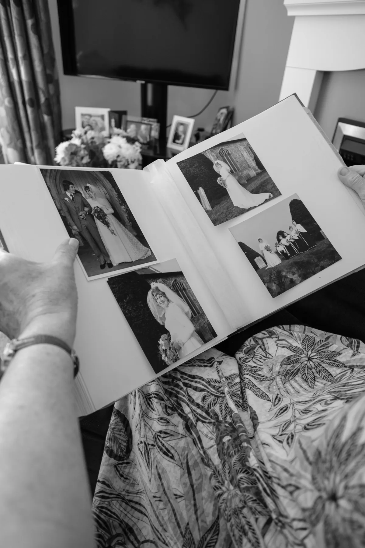 Hands holding open a photo album of black and white wedding photographs