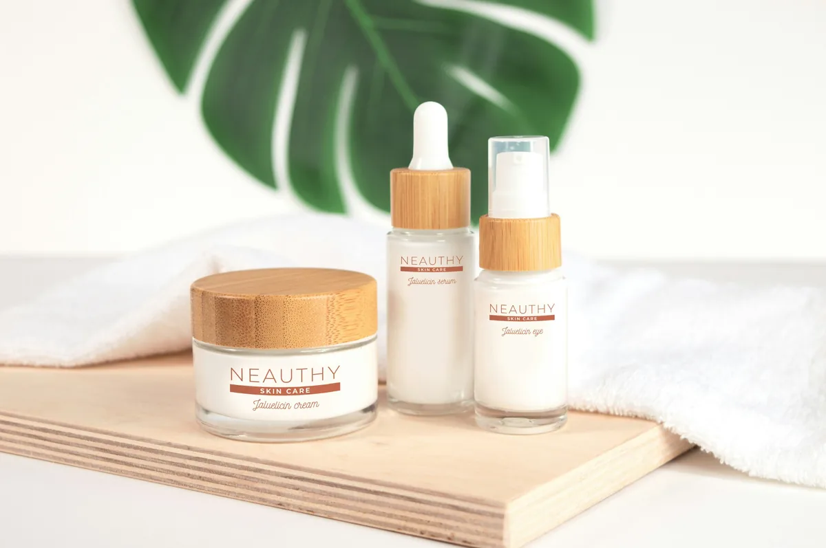 Skincare bottles and a cream jar on a wooden board