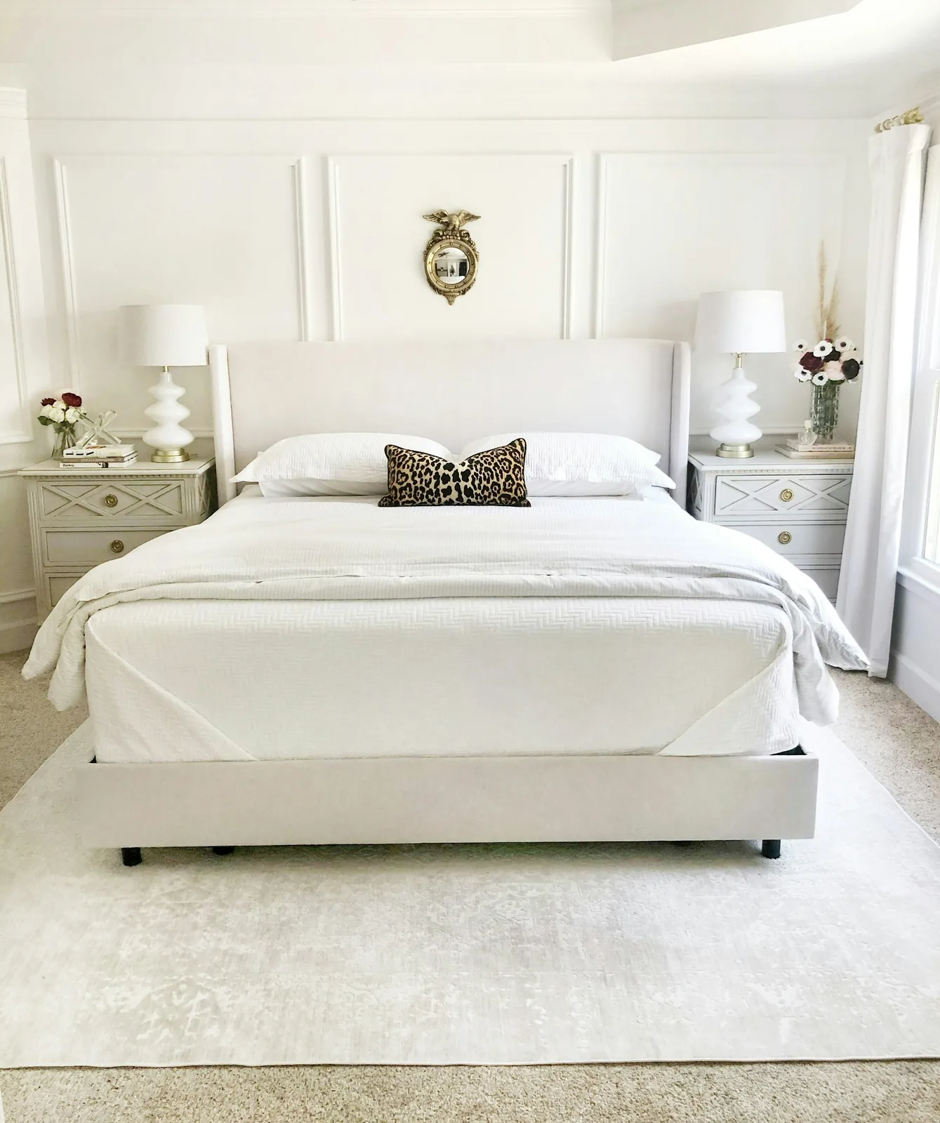 A neatly made bed dressed in white bedding in a bright bedroom