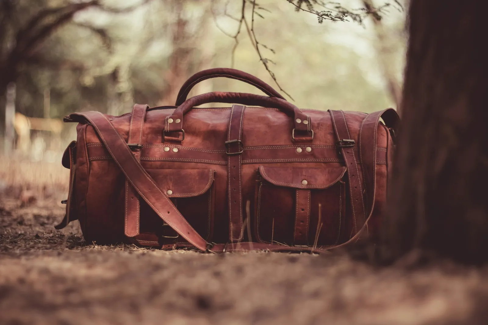 A brown leather travel bag with brass hardware