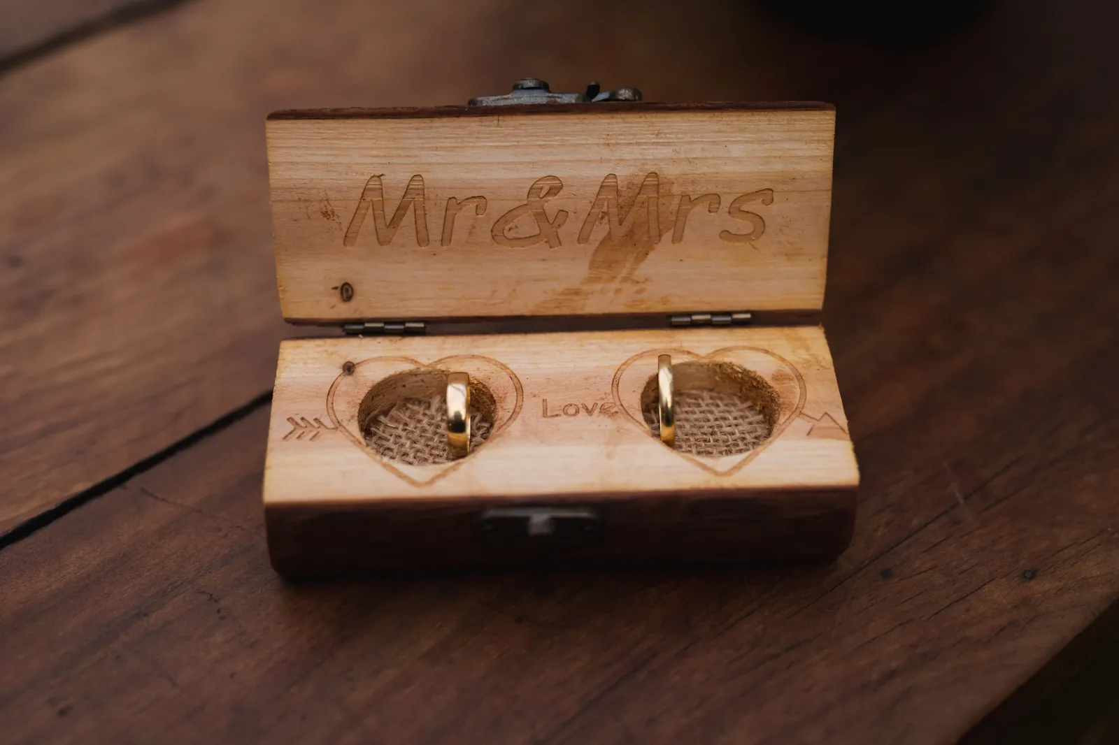 An engraved wooden box holding two wedding rings