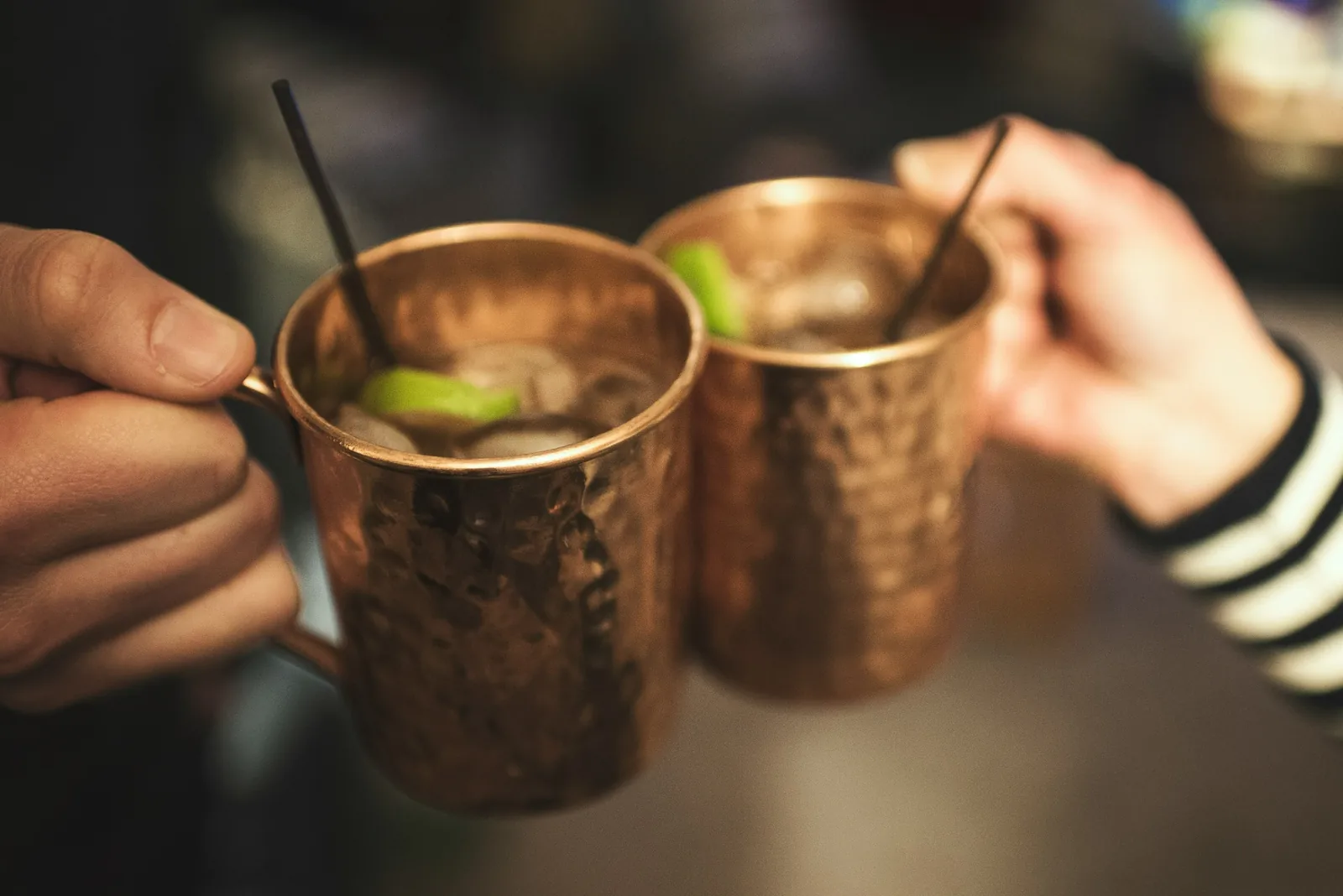 Two hammered copper mugs on a dark surface